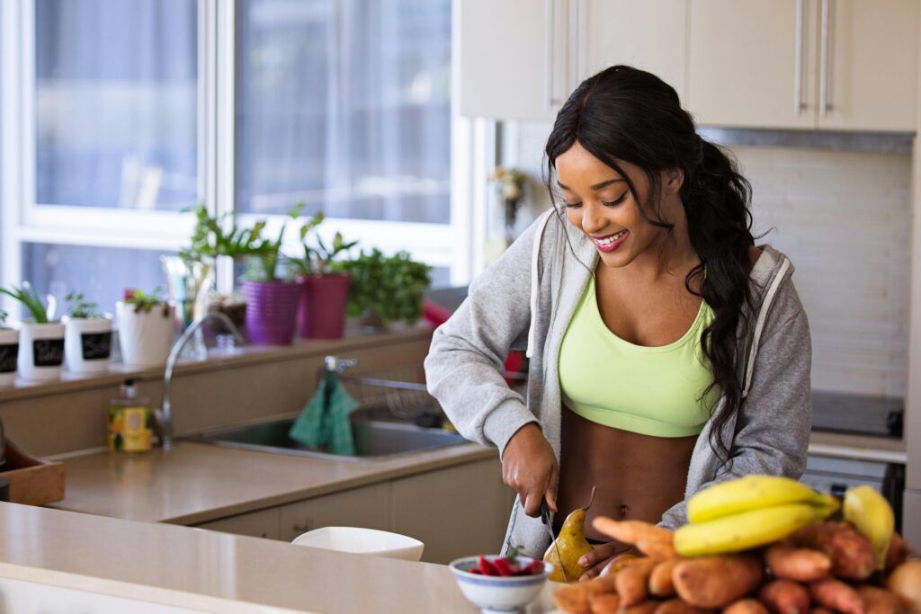pexels-photo-1153369-1153369 Smiling woman preparing fresh fruit in a sunlit kitchen, embodying a healthy lifestyle.